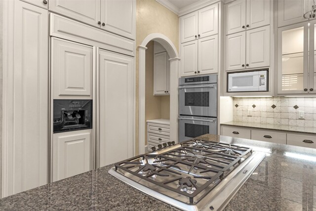 6616 Queensclub Dr, Houston, TX 77069 - kitchen with built in appliances, arched walkways, decorative backsplash, white cabinetry, and glass insert cabinets