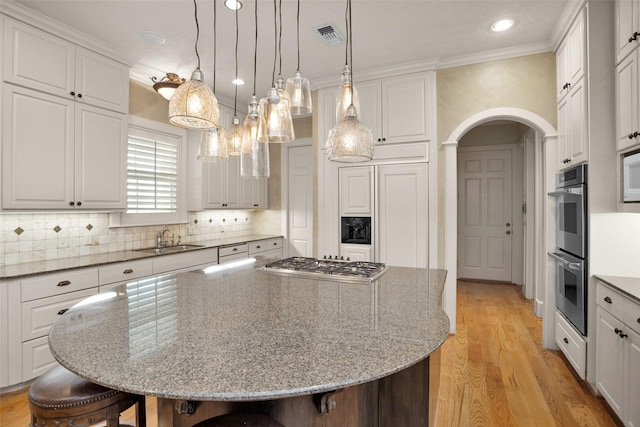 6616 Queensclub Dr, Houston, TX 77069 - kitchen with appliances with stainless steel finishes, a kitchen bar, arched walkways, a center island, and light wood finished floors