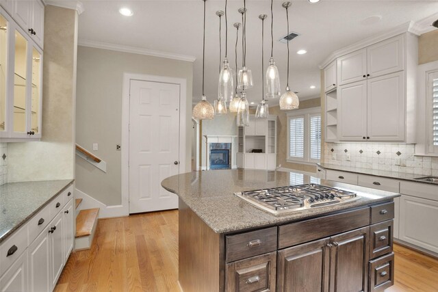 6616 Queensclub Dr, Houston, TX 77069 - kitchen featuring stainless steel gas stovetop, ornamental molding, light wood-type flooring, white cabinetry, and backsplash