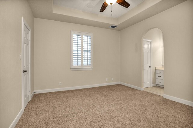6616 Queensclub Dr, Houston, TX 77069 - unfurnished bedroom with a tray ceiling, light carpet, arched walkways, and ensuite bath