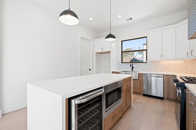 5505 Kansas St, Houston, TX 77007 - kitchen featuring appliances with stainless steel finishes, beverage cooler, backsplash, light wood-type flooring, and recessed lighting