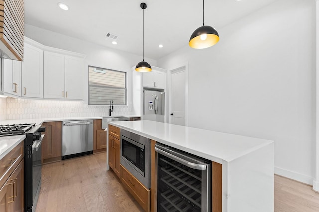 5505 Kansas St, Houston, TX 77007 - kitchen featuring stainless steel appliances, wine cooler, light wood-style flooring, tasteful backsplash, and light countertops