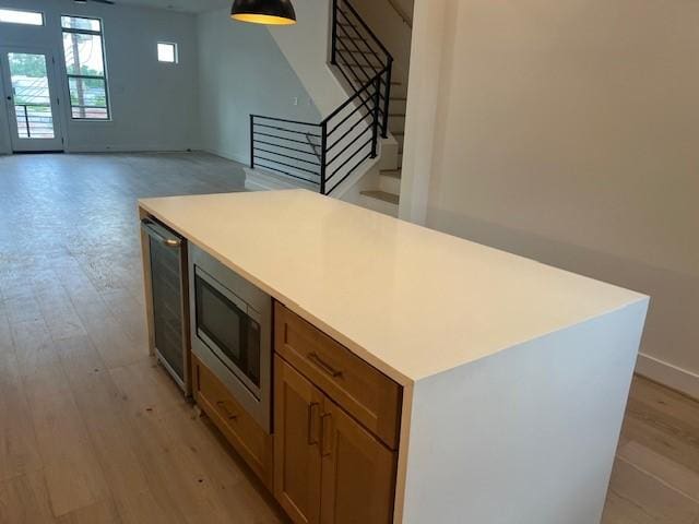 5505 Kansas St, Houston, TX 77007 - kitchen featuring stainless steel microwave, light countertops, light wood finished floors, brown cabinets, and wine cooler