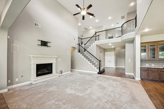 4906 Lodge Lake Dr, Fulshear, TX 77441 - unfurnished living room with a high ceiling, a ceiling fan, dark wood-style floors, stairway, and a glass covered fireplace