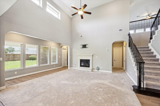 4906 Lodge Lake Dr, Fulshear, TX 77441 - unfurnished living room with a ceiling fan, high vaulted ceiling, stairway, arched walkways, and a glass covered fireplace