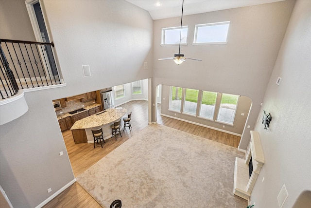 4906 Lodge Lake Dr, Fulshear, TX 77441 - living area featuring a high ceiling, ceiling fan, light wood-style flooring, arched walkways, and stairway