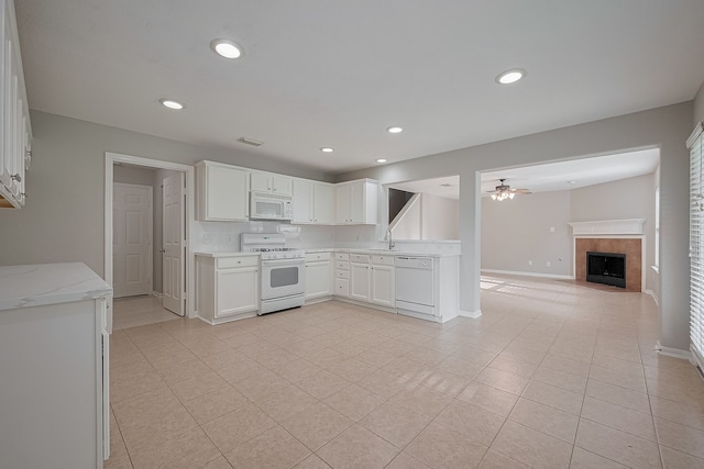 9714 Angleside Ln, Sugar Land, TX 77498 - kitchen with white appliances, a ceiling fan, light tile patterned floors, a tiled fireplace, and white cabinetry