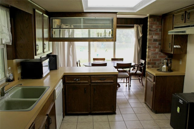 216 N St, Columbus, TX 78934 - kitchen featuring under cabinet range hood, white dishwasher, healthy amount of natural light, and light tile patterned floors