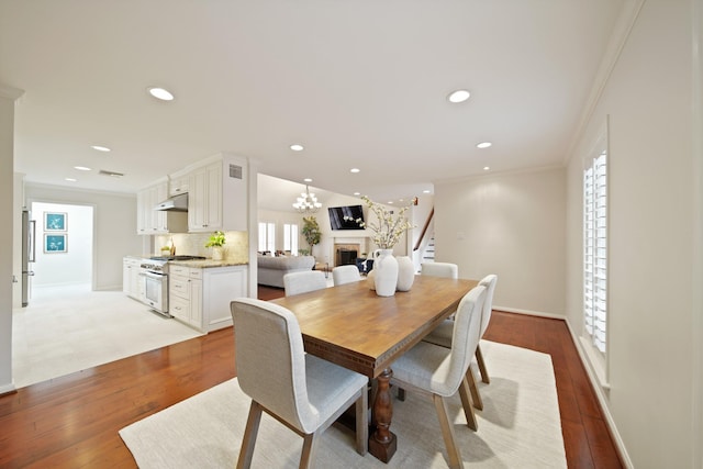 2200 Potomac Dr, Houston, TX 77057 - dining space with crown molding, wood finished floors, recessed lighting, a fireplace, and a chandelier