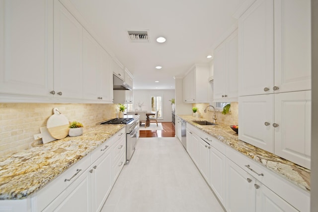 2200 Potomac Dr, Houston, TX 77057 - kitchen featuring under cabinet range hood, appliances with stainless steel finishes, white cabinets, backsplash, and recessed lighting