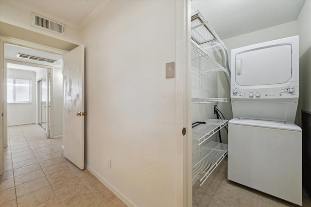 4040 San Felipe St Unit 135, Houston, TX 77027 - laundry area featuring estacked washer and dryer, ornamental molding, and light tile patterned floors