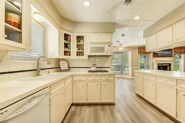 11823 Blair Meadow Dr, Meadows Place, TX 77477 - kitchen featuring white appliances, a textured ceiling, light wood-style floors, tasteful backsplash, and a fireplace