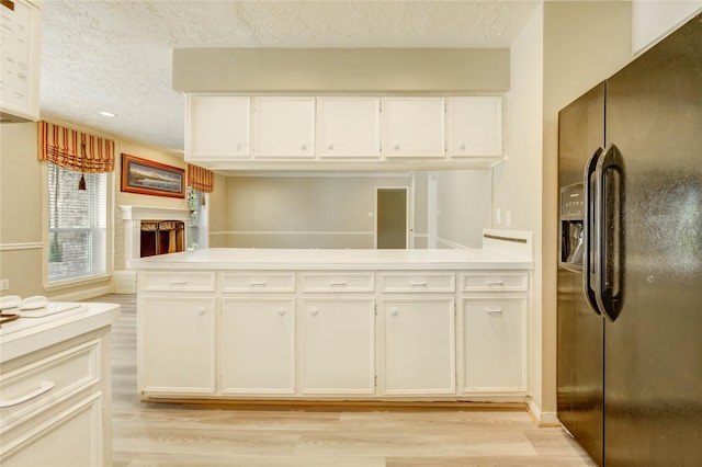 11823 Blair Meadow Dr, Meadows Place, TX 77477 - kitchen featuring black refrigerator with ice dispenser, light wood-style flooring, a textured ceiling, light countertops, and white cabinets
