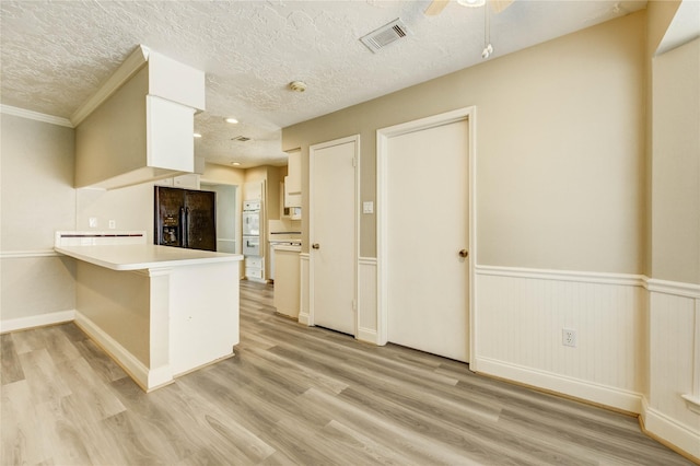 11823 Blair Meadow Dr, Meadows Place, TX 77477 - kitchen with black fridge, a peninsula, a textured ceiling, light wood finished floors, and light countertops
