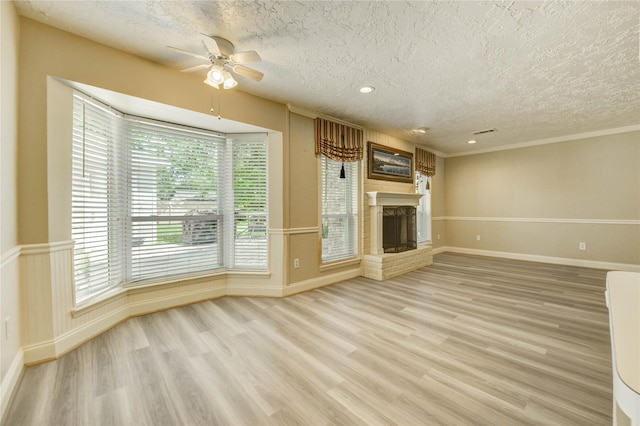 11823 Blair Meadow Dr, Meadows Place, TX 77477 - unfurnished living room with a textured ceiling, ceiling fan, light wood-style flooring, a fireplace with raised hearth, and crown molding