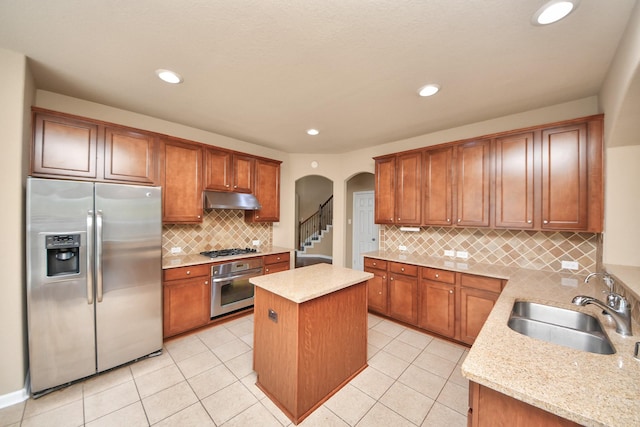 30041 Willow Walk Ln, Brookshire, TX 77423 - kitchen featuring appliances with stainless steel finishes, under cabinet range hood, arched walkways, a kitchen island, and tasteful backsplash
