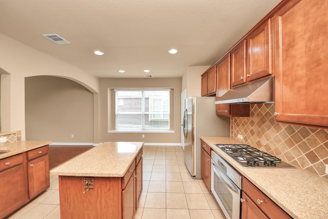 30041 Willow Walk Ln, Brookshire, TX 77423 - kitchen with stainless steel appliances, under cabinet range hood, backsplash, light tile patterned flooring, and a center island