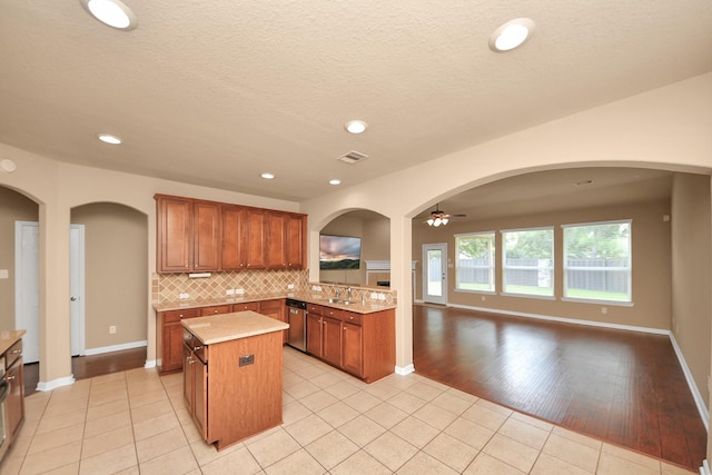 30041 Willow Walk Ln, Brookshire, TX 77423 - kitchen with ceiling fan, a center island, light tile patterned floors, tasteful backsplash, and brown cabinetry