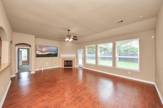 30041 Willow Walk Ln, Brookshire, TX 77423 - unfurnished living room with a ceiling fan, dark wood-style floors, a tile fireplace, and healthy amount of natural light