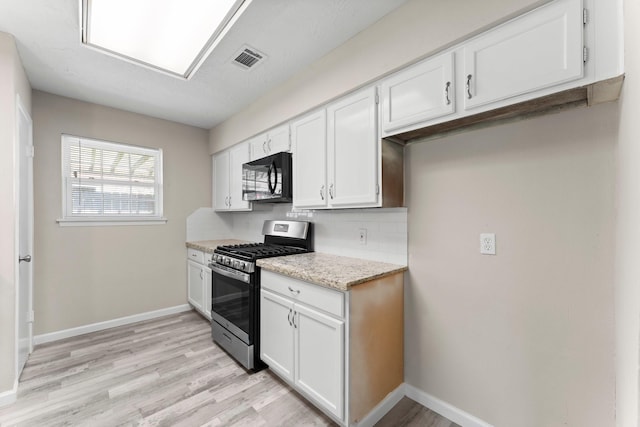 3527 Acorn Way Ln, Spring, TX 77389 - kitchen featuring stainless steel gas stove, black microwave, white cabinetry, and light wood finished floors