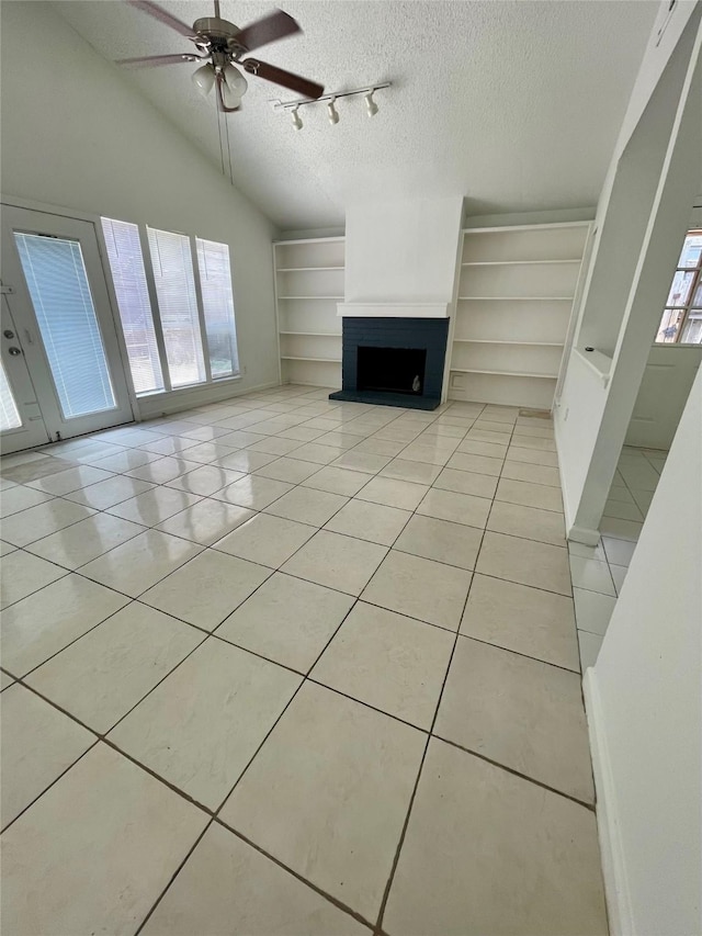 4202 Boone Rd, Houston, TX 77072 - unfurnished living room featuring light tile patterned flooring, a fireplace with raised hearth, a textured ceiling, a ceiling fan, and built in shelves