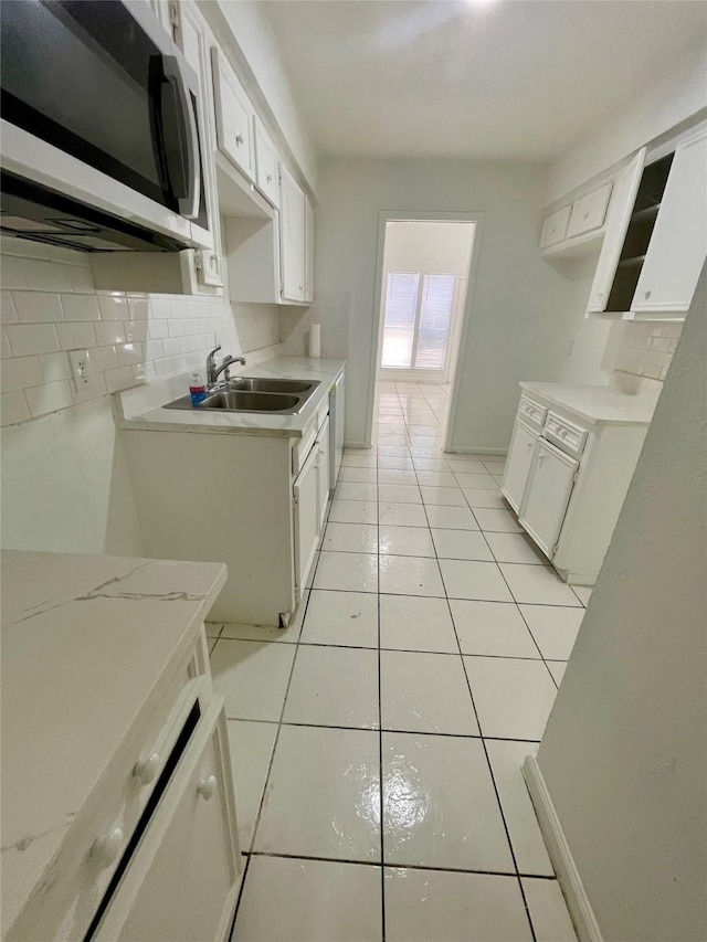 4202 Boone Rd, Houston, TX 77072 - kitchen featuring stainless steel microwave, backsplash, light tile patterned flooring, and white cabinetry