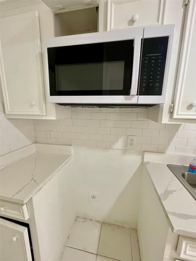 4202 Boone Rd, Houston, TX 77072 - kitchen view of white microwave, white cabinets, backsplash, and light stone counters