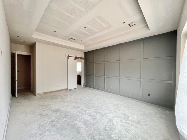 1162 Rd 6604, Dayton, TX 77535 - unfurnished bedroom with a decorative wall, unfinished concrete flooring, a raised ceiling, and a barn door