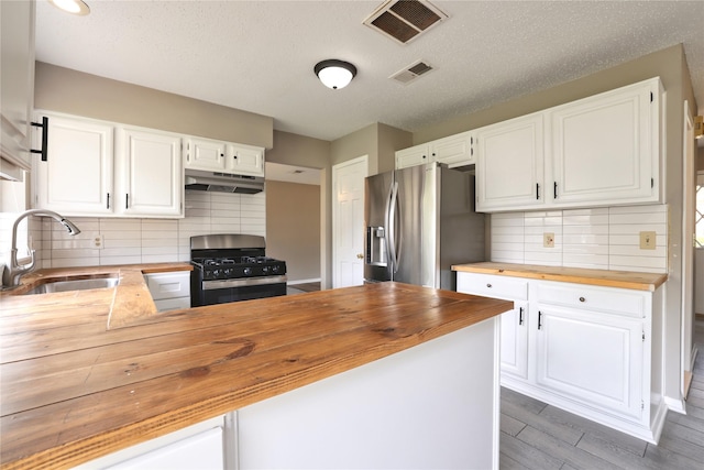 15918 Pinyon Creek Dr, Houston, TX 77095 - kitchen with wooden counters, stainless steel fridge, gas stove, under cabinet range hood, and backsplash