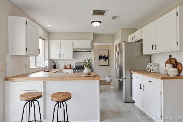 15918 Pinyon Creek Dr, Houston, TX 77095 - kitchen featuring under cabinet range hood, a peninsula, freestanding refrigerator, stove, and decorative backsplash
