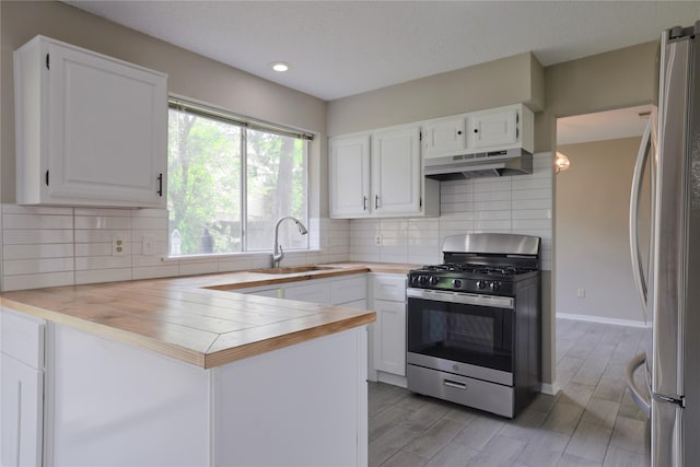 15918 Pinyon Creek Dr, Houston, TX 77095 - kitchen with appliances with stainless steel finishes, under cabinet range hood, a peninsula, white cabinets, and recessed lighting