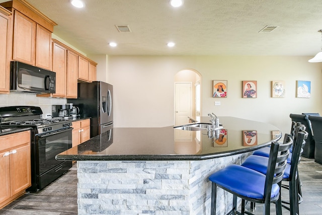 10219 Kentington Oak Dr, Humble, TX 77396 - kitchen featuring black appliances, arched walkways, dark wood-type flooring, a kitchen bar, and recessed lighting
