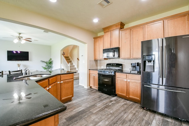 10219 Kentington Oak Dr, Humble, TX 77396 - kitchen with black appliances, arched walkways, wood finished floors, ceiling fan, and recessed lighting