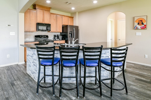 10219 Kentington Oak Dr, Humble, TX 77396 - kitchen featuring range, black microwave, fridge with ice dispenser, arched walkways, and an island with sink