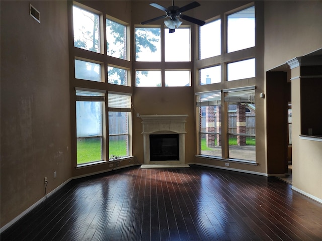 9510 Gentry Shadows Ln, Humble, TX 77396 - unfurnished living room with ceiling fan, wood-type flooring, a glass covered fireplace, and a high ceiling