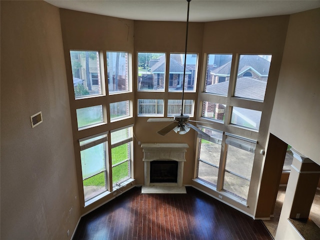 9510 Gentry Shadows Ln, Humble, TX 77396 - unfurnished living room featuring a ceiling fan, dark wood-style flooring, a fireplace with raised hearth, and a high ceiling