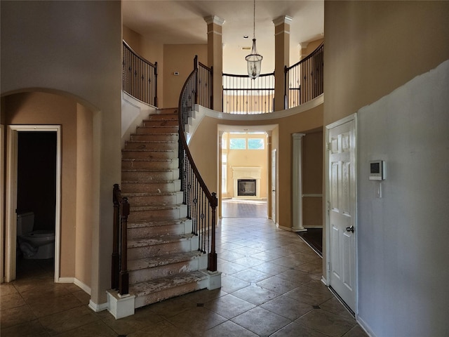 9510 Gentry Shadows Ln, Humble, TX 77396 - foyer with stairs, dark tile patterned flooring, a chandelier, a high ceiling, and decorative columns