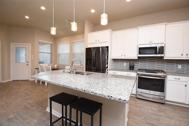 7011 Golden Groundsel Dr, Katy, TX 77493 - kitchen with appliances with stainless steel finishes, white cabinets, an island with sink, recessed lighting, and lofted ceiling