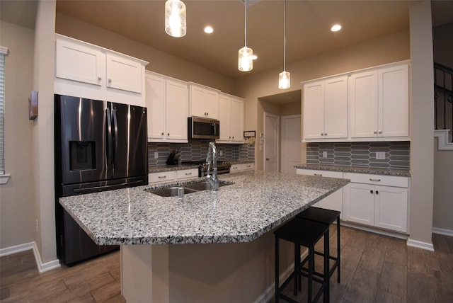 7011 Golden Groundsel Dr, Katy, TX 77493 - kitchen with appliances with stainless steel finishes, tasteful backsplash, dark wood-type flooring, white cabinetry, and a kitchen breakfast bar