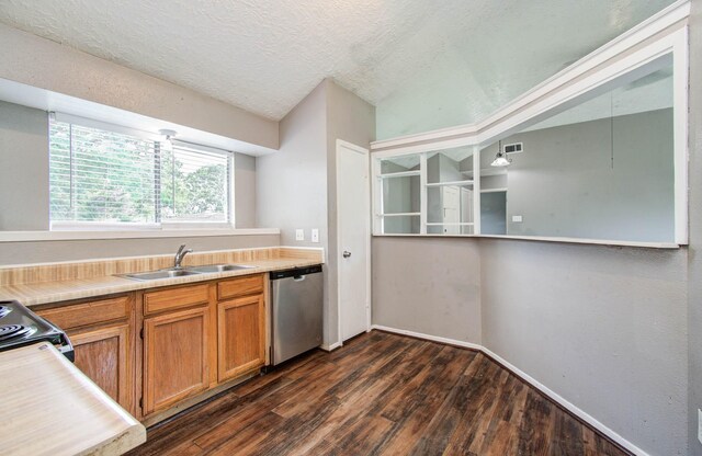 906 Dixie Dr, League City, TX 77573 - kitchen featuring dishwasher, dark wood-type flooring, brown cabinetry, light countertops, and a textured ceiling