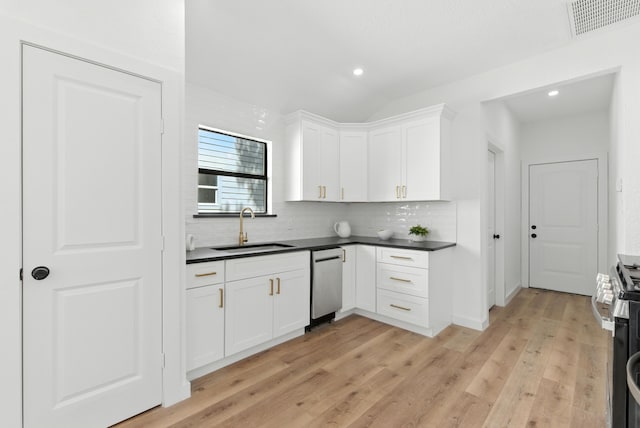 1311 E 35th St, Houston, TX 77022 - kitchen featuring appliances with stainless steel finishes, dark countertops, decorative backsplash, white cabinetry, and lofted ceiling
