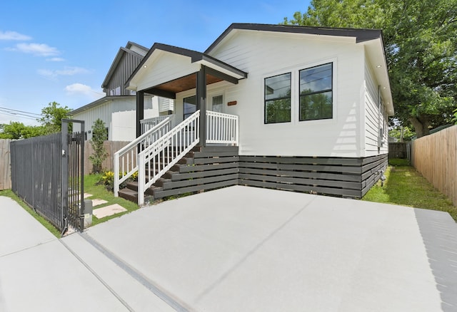 1311 E 35th St, Houston, TX 77022 - view of front of house featuring a fenced backyard, a porch, a patio area, and board and batten siding