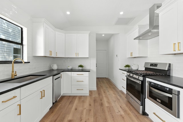 1311 E 35th St, Houston, TX 77022 - kitchen with stainless steel appliances, wall chimney range hood, dark countertops, recessed lighting, and vaulted ceiling
