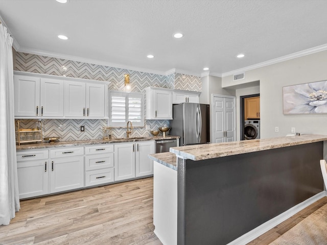 441 Jeanie Lynne Cir, Galveston, TX 77554 - kitchen with appliances with stainless steel finishes, crown molding, washer / clothes dryer, white cabinetry, and tasteful backsplash
