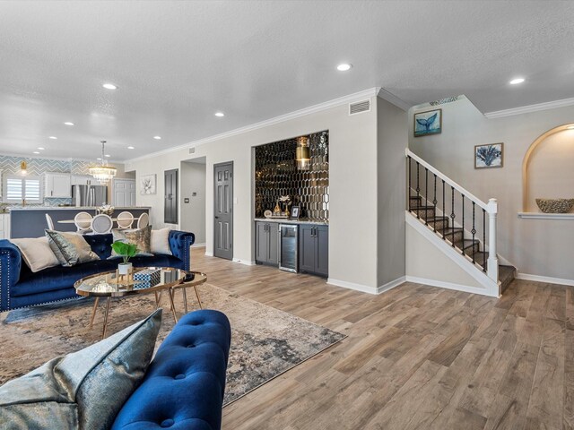 441 Jeanie Lynne Cir, Galveston, TX 77554 - living area with beverage cooler, a dry bar, crown molding, stairs, and light wood finished floors