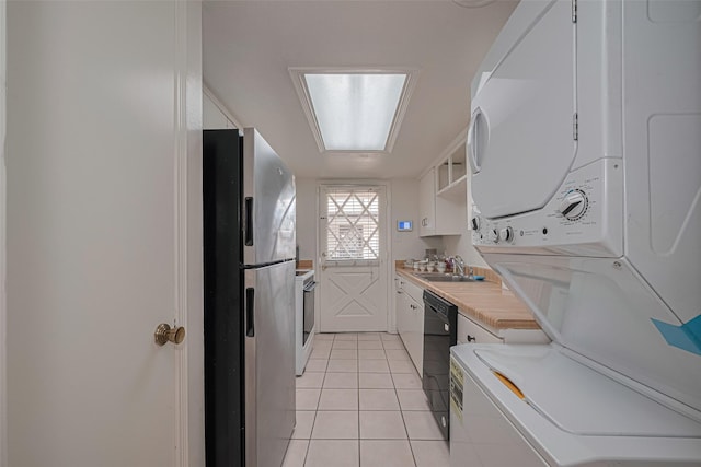 12633 Memorial Dr Unit 250, Houston, TX 77024 - kitchen with freestanding refrigerator, stacked washer and clothes dryer, light countertops, black dishwasher, and light tile patterned floors