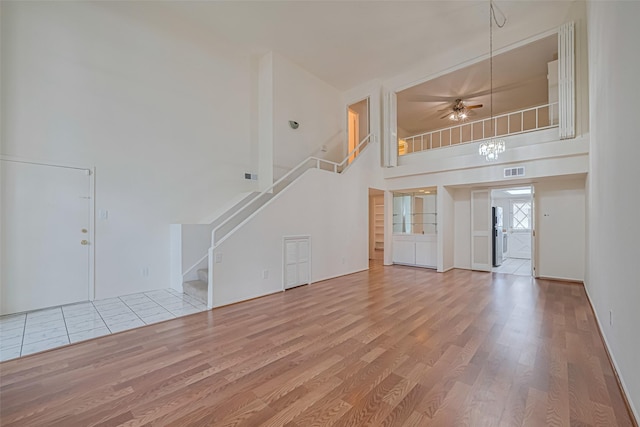12633 Memorial Dr Unit 250, Houston, TX 77024 - unfurnished living room with stairway, wood finished floors, a high ceiling, and a ceiling fan