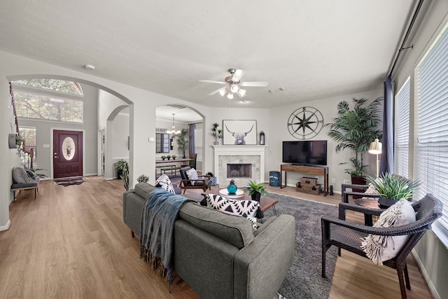 15026 Grape Orchard Ct, Cypress, TX 77433 - living room featuring arched walkways, a ceiling fan, wood finished floors, and a tile fireplace