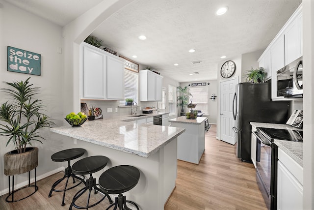 15026 Grape Orchard Ct, Cypress, TX 77433 - kitchen featuring stainless steel appliances, a center island, recessed lighting, a peninsula, and light wood-style flooring