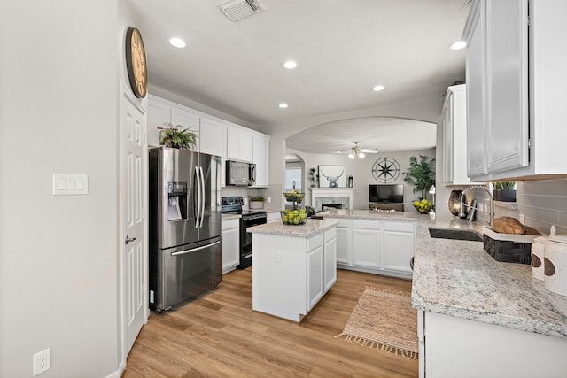 15026 Grape Orchard Ct, Cypress, TX 77433 - kitchen with appliances with stainless steel finishes, arched walkways, a ceiling fan, a center island, and white cabinetry